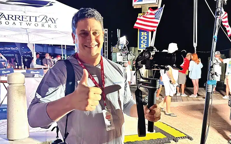 A videographer from Bluewater Yacht Sales giving a thumbs up while holding a professional camera during a yacht event